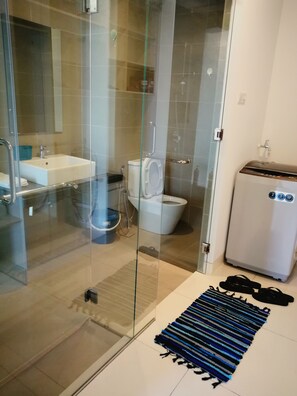 A modern bathroom with a glass shower enclosure, a white sink, and a toilet. - GT Home Tropicana Garden (Petaling Jaya)