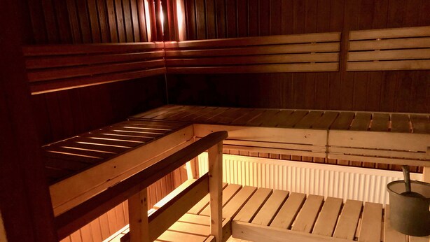 A sauna with wooden benches and a bench with a metal bucket. - Hotelli Äänekoski (Äänekoski)