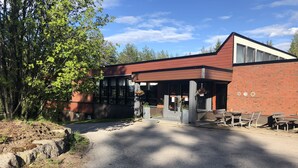A modern building with a brick facade, large windows, and outdoor seating. - Hotelli Äänekoski (Äänekoski)