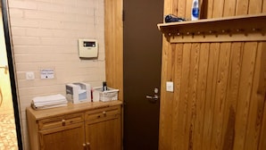 A bathroom with a wooden vanity, a towel rack, a shelf with toiletries, and a door. - Hotelli Äänekoski (Äänekoski)