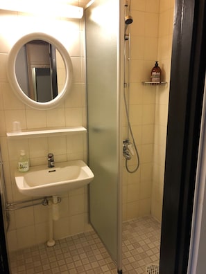 A bathroom with a white sink, a mirror, and a glass-enclosed shower.