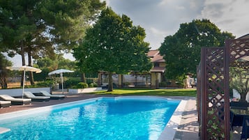 Una piscina al aire libre de temporada, sombrillas