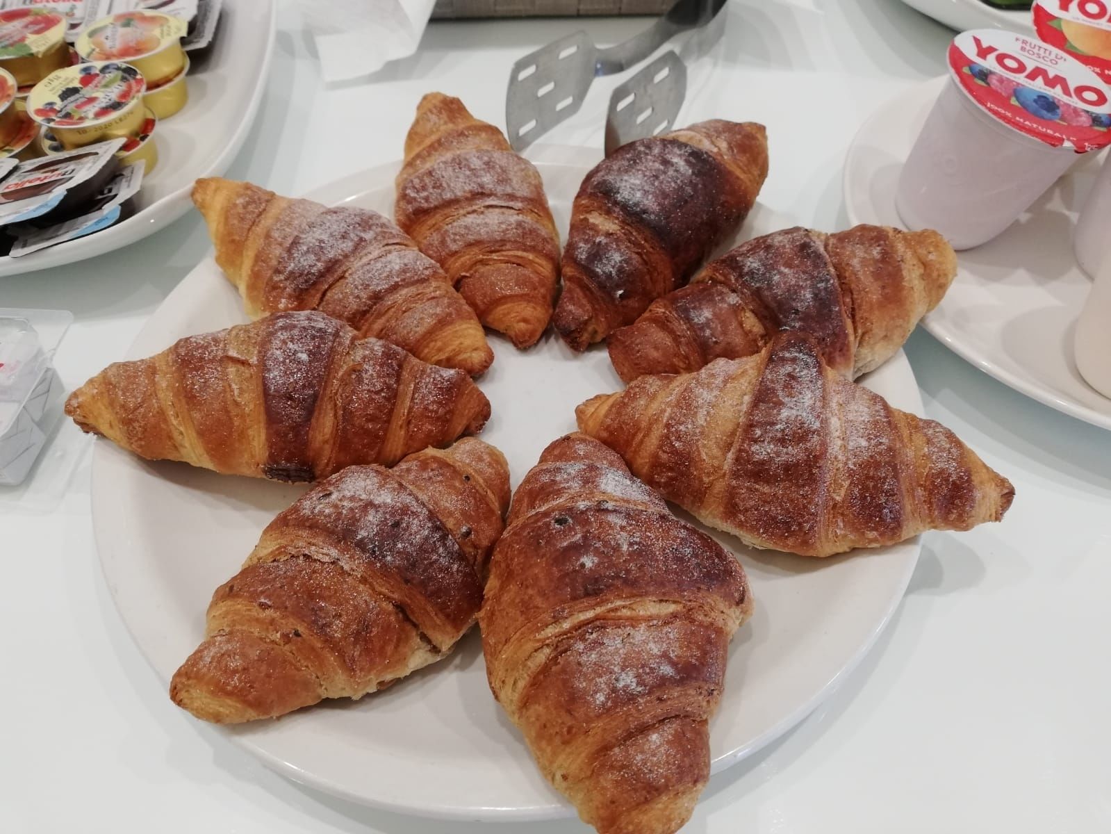 Une assiette de croissants dorés et croustillants, disposés sur une assiette blanche.