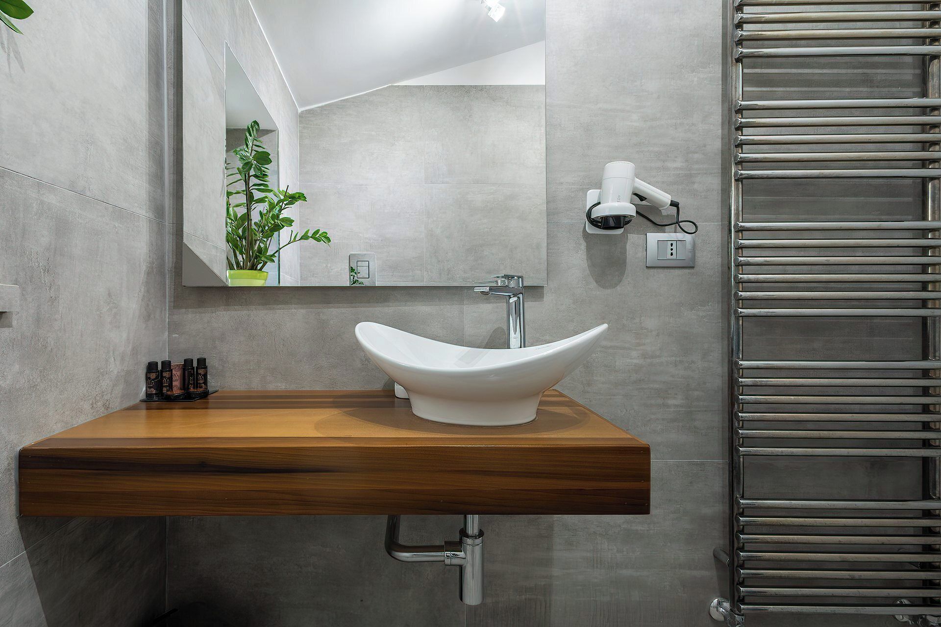 A bathroom with a white vessel sink, a wooden countertop, a mirror, a towel dispenser, and a towel rack.