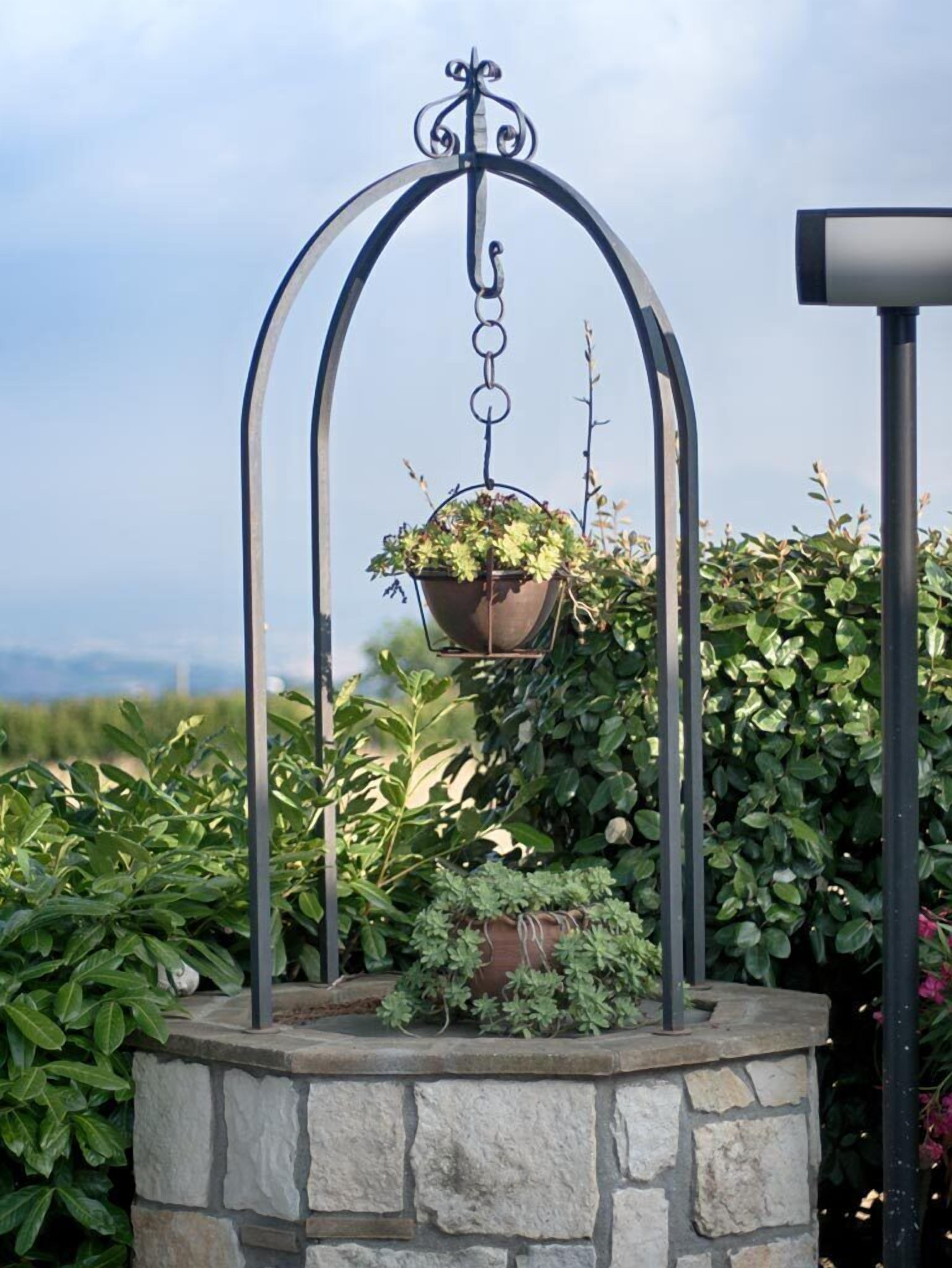 A hanging planter with a stone base, surrounded by lush greenery.