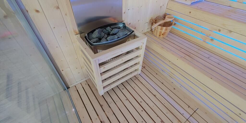 A sauna room with a wooden floor, a stone basin, and a wooden bench.
