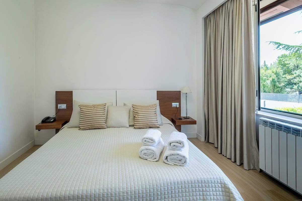 Une chambre d’hôtel avec un grand lit, une table de chevet avec une lampe et une vue sur la verdure.