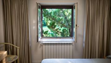 Un dormitorio con ventana, cortinas, radiador y cama.