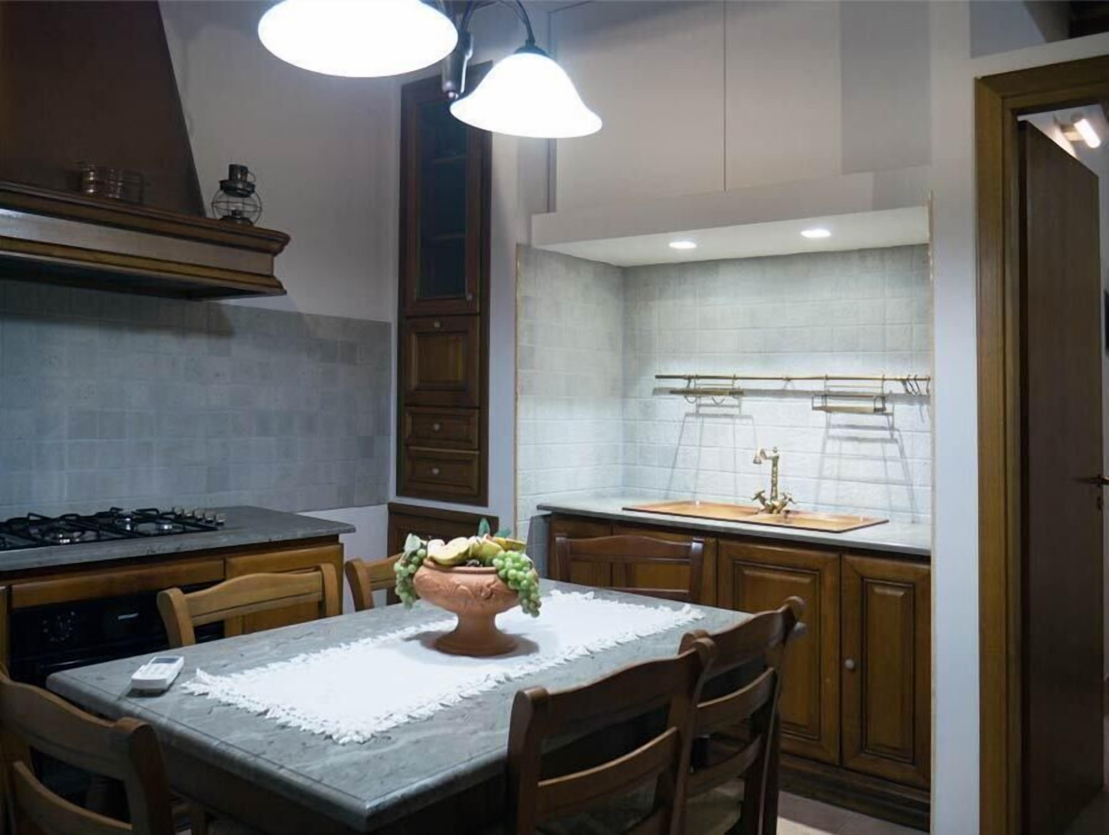A kitchen with a gas stove, wooden cabinets, a dining table with chairs, and pendant lighting.