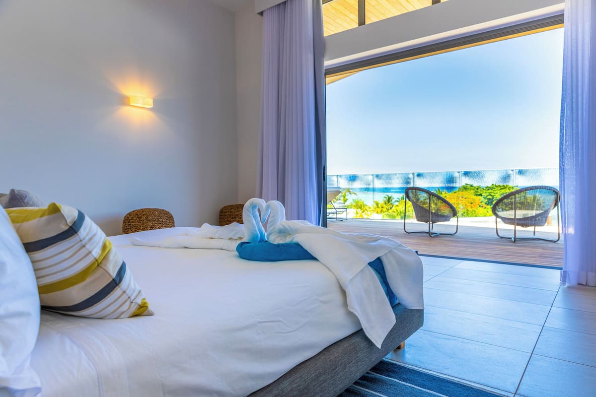A hotel room with a bed, a view of the balcony, and a chair.
