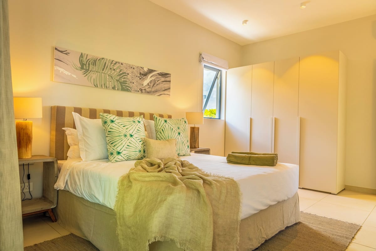 A bedroom with a bed, bedside lamps, a window, and a wardrobe.