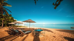 A beach with lounge chairs and umbrellas, a table, and a view of the ocean. - Manta Cove by Horizon Holidays (Black River)