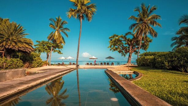 A pool with a clear view of the ocean and palm trees. - Manta Cove by Horizon Holidays (Black River)