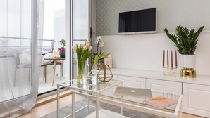A modern living room with a glass coffee table, a laptop, a notebook, and decorative items including a vase with flowers and a potted plant. - MM House - Adults Only (Zagreb)
