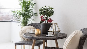 A round table with a potted plant, a candle, and two cups on a balcony with wicker chairs. - MM House - Adults Only (Zagreb)