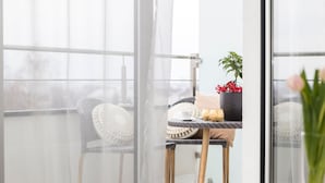 A balcony with wicker chairs, a small table with a cushion, a potted plant with red berries, and a view of the outdoors. - MM House - Adults Only (Zagreb)