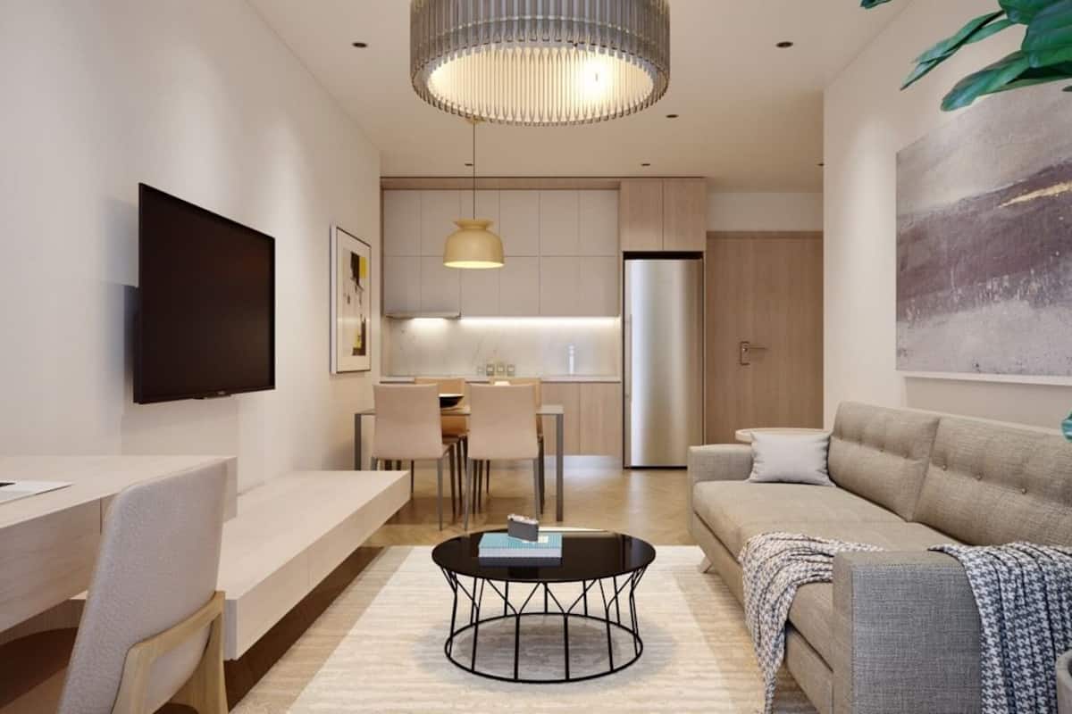 A modern living room with a flat-screen TV, a dining area, and a kitchen in the background.