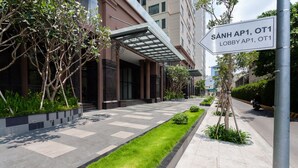 A modern building with a covered entrance, a well-maintained lawn, and a clear pathway leading to the entrance. - Ami Splendid Rooftop Garden (Ho Chi Minh City)