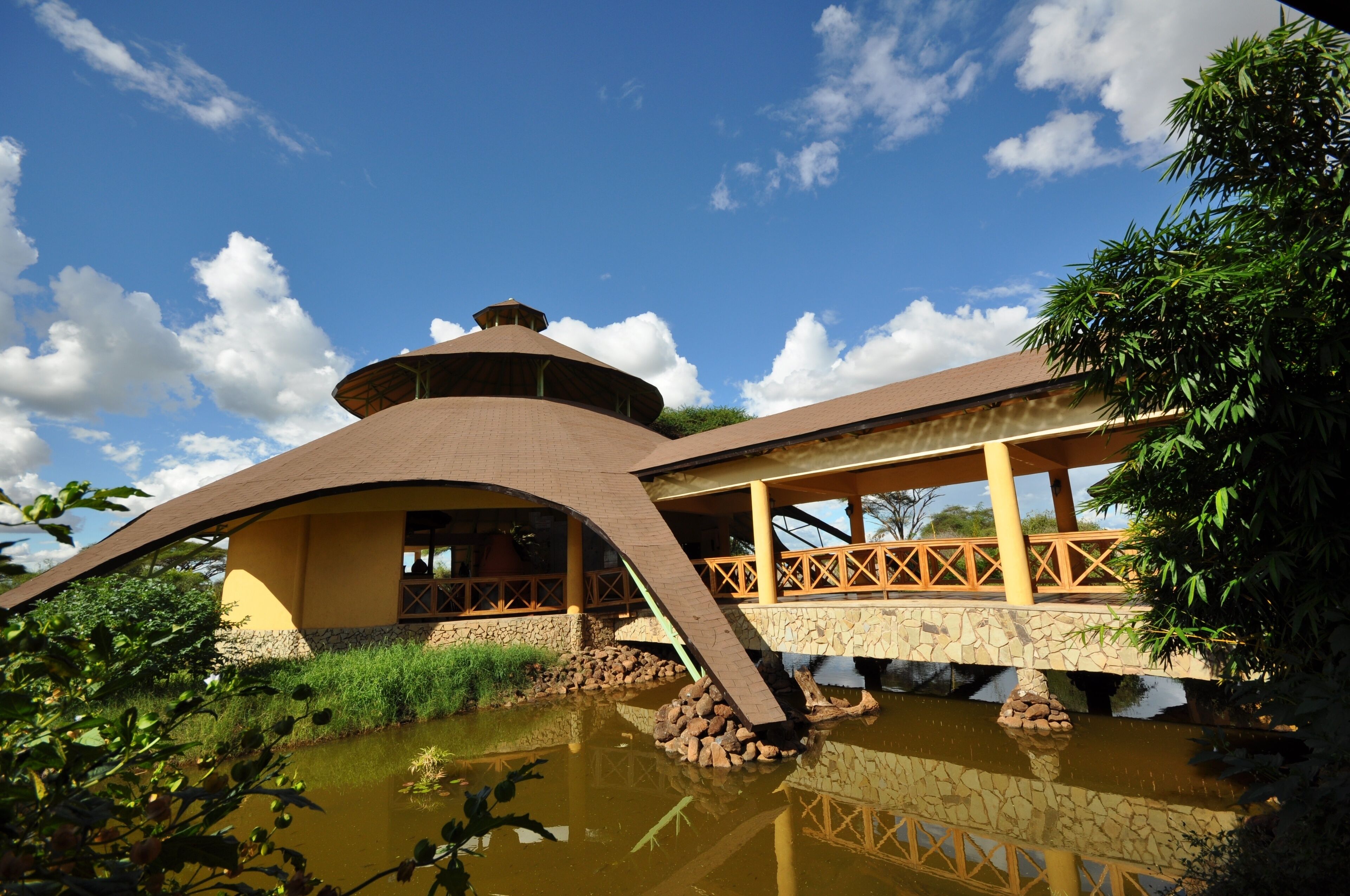 A building with a curved roof and a bridge over a pond.