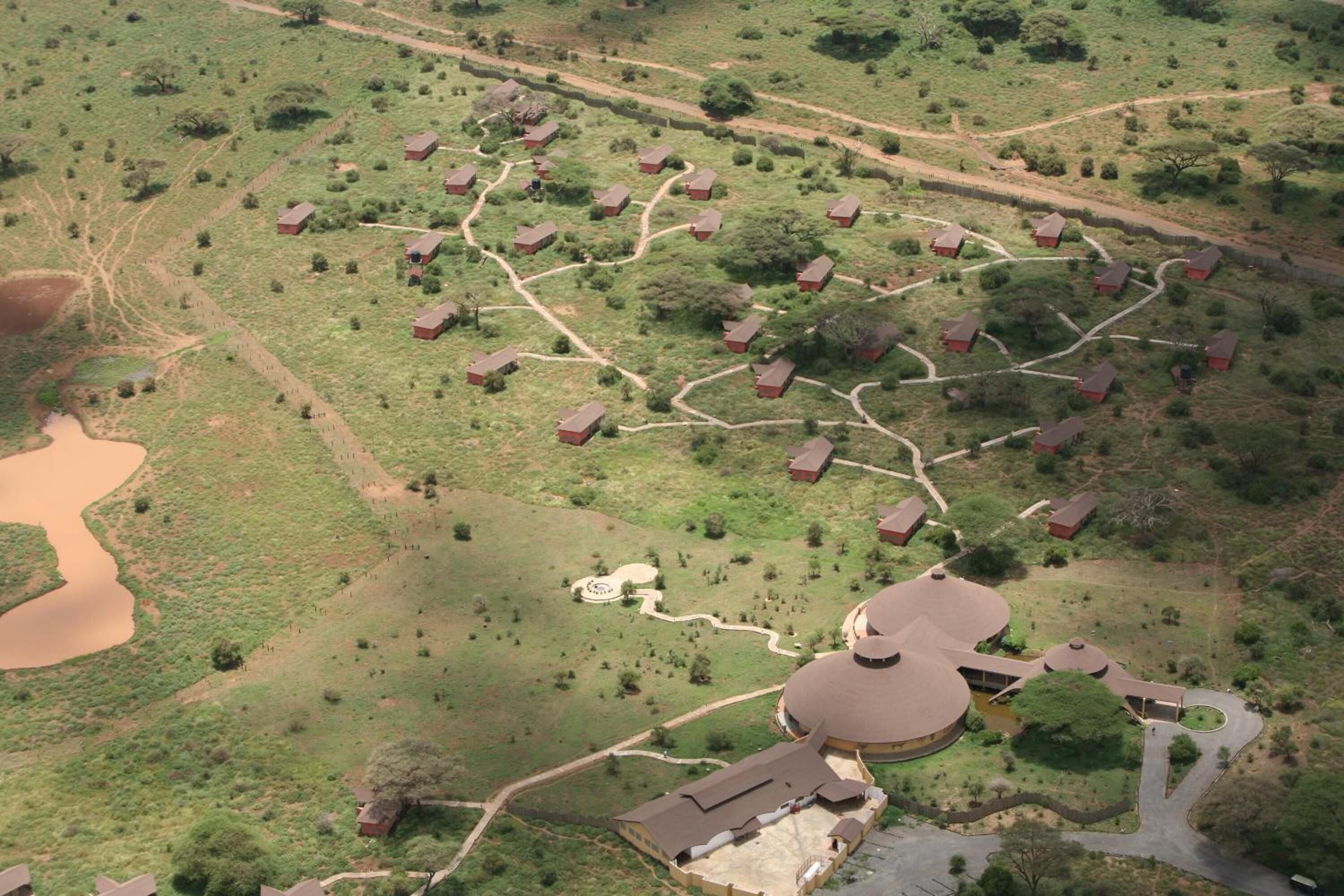 Vista aérea de una zona rural con un edificio central rodeado de pequeñas casas conectadas por senderos.