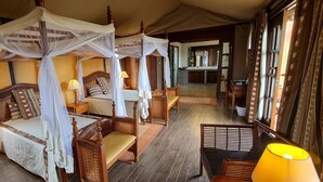 A four-poster bed with a canopy, a bedside table with a lamp, and a bench.