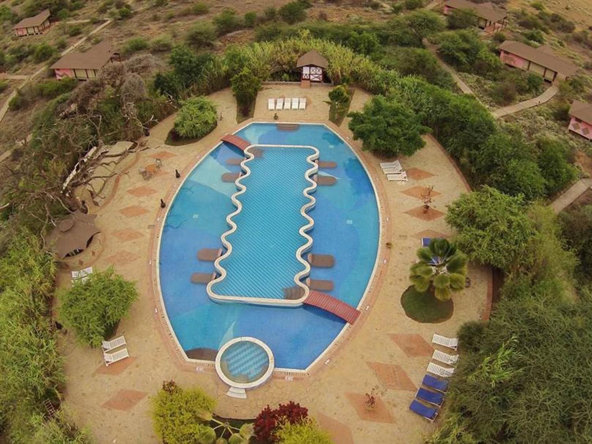 Una piscina octagonal con una isla central y sillones de descanso alrededor.