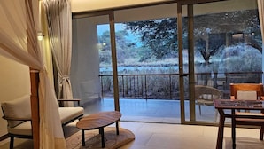 A spacious balcony with a view of trees and a fence, furnished with a sofa, chairs, and a table.