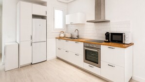 Eine moderne Küche mit weißen Schränken, einer Holz Arbeitsplatte, einem Einbauofen, einer Mikrowelle und einer Edelstahl-Dunstabzugshaube.