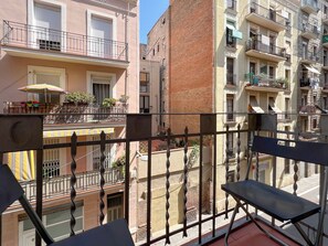 A balcony with a view of adjacent buildings, a table with chairs, and a potted plant. - Stay U-nique Apartments Begur (Barcelona)