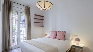 Ein Schlafzimmer mit einem Bett, Nachttischlampen, einem Fenster mit Vorhängen und Blick nach draußen.