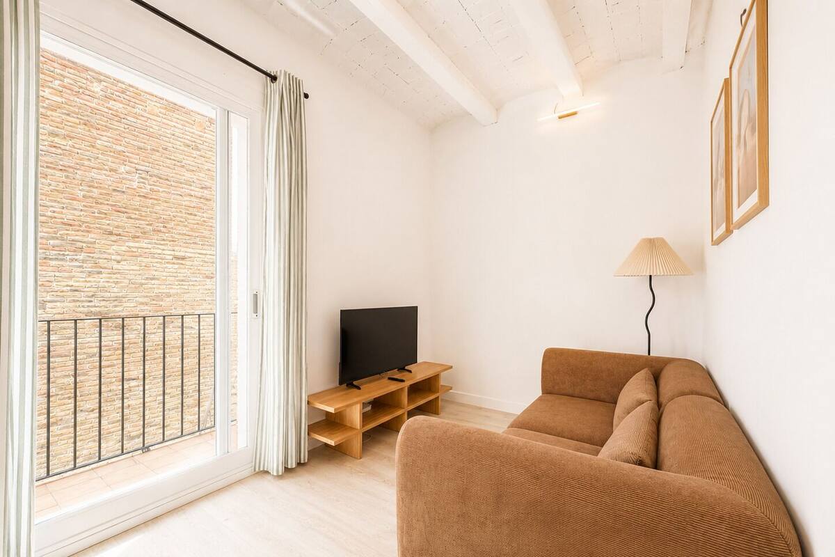 Una sala de estar moderna con sofá, televisor y lámpara.