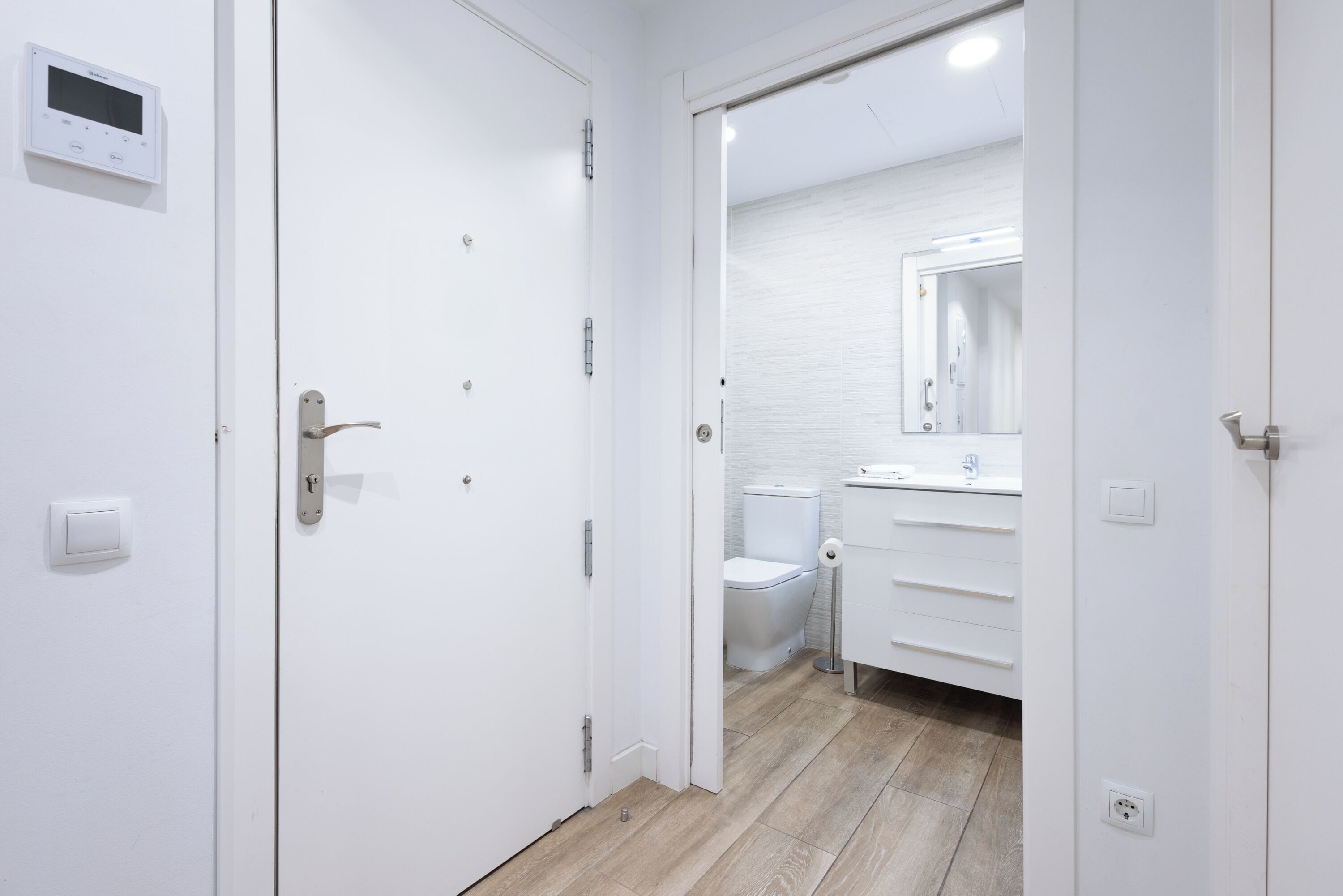 A modern bathroom with a toilet, sink, and mirror.