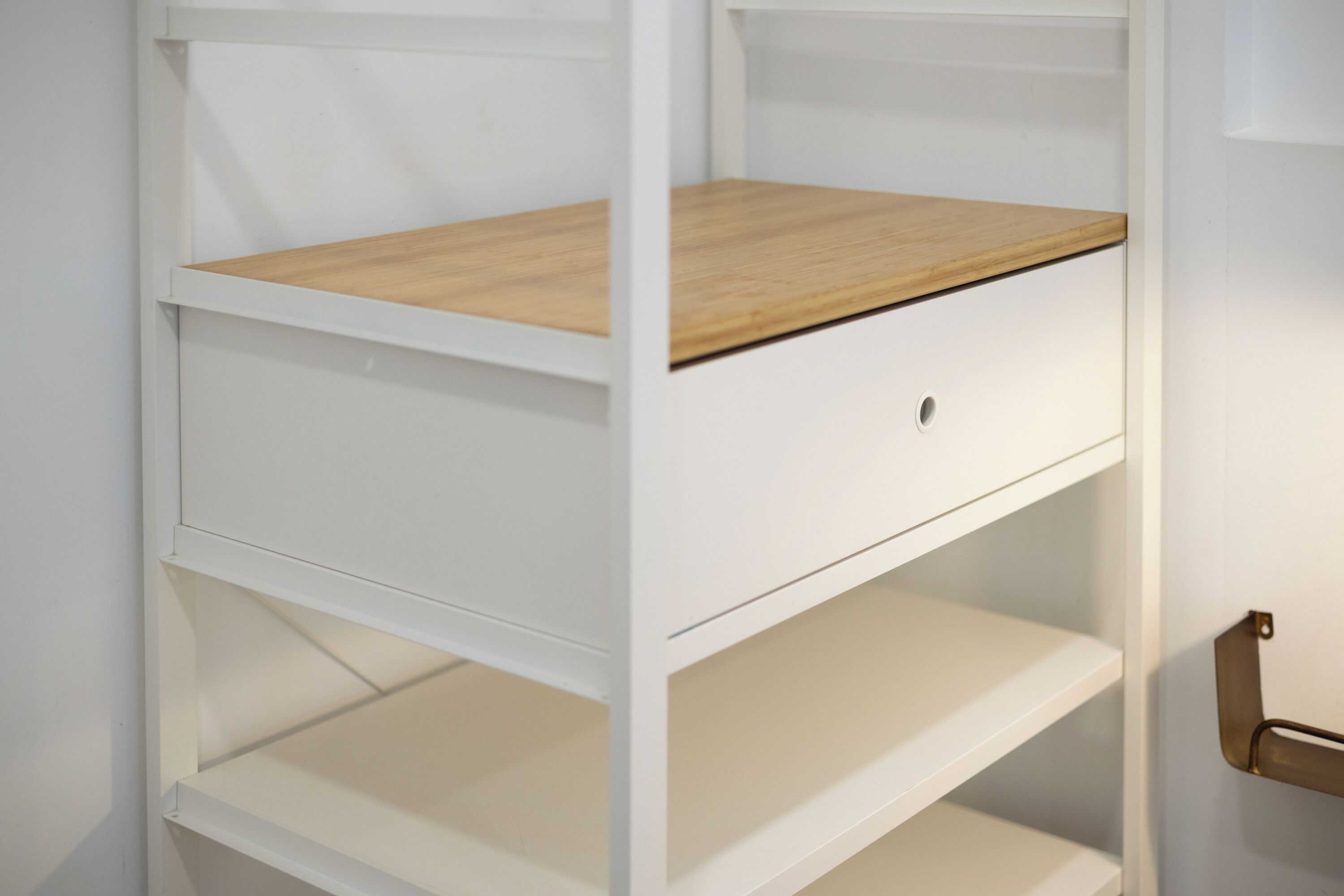Een witte schapenkast met een houten bovenblad en een klein afsluitbaar lade.