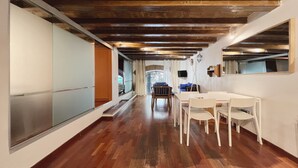 A spacious hallway with wooden flooring, a dining area with white chairs, and a large mirror on the right wall. - Stay U-nique Apartments Plaça Universitat (Barcelona)