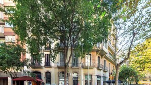 A multi-story building with balconies, a street with parked motorcycles, and a pedestrian crossing. - Stay U-nique Apartments Plaça Universitat (Barcelona)
