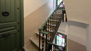 Un escalier avec une rampe verte et une porte dotée d’une poignée circulaire.