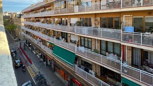 Un hôtel à plusieurs étages, doté de balcons, d’un auvent vert et donnant sur la rue, où l’on peut voir des véhicules et des piétons.