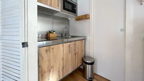 Une cuisine de taille réduite, dotée de meubles en bois, d’un évier en acier inoxydable et d’un four à micro-ondes.