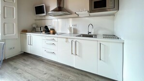 A modern kitchen with white cabinets, a stainless steel range hood, a built-in microwave, and a sink. - Stay U-nique Apartments Fontrodona (Barcelona)