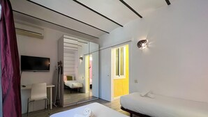 A modern hotel room with a large bed, a desk, a chair, a TV, and a mirror. - Stay U-nique Apartments Fontrodona (Barcelona)