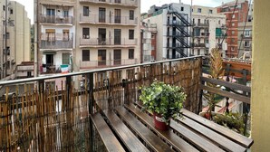 A balcony with wooden benches and a potted plant, overlooking a residential area with multi-story buildings. - Stay U-nique Apartments Fontrodona (Barcelona)