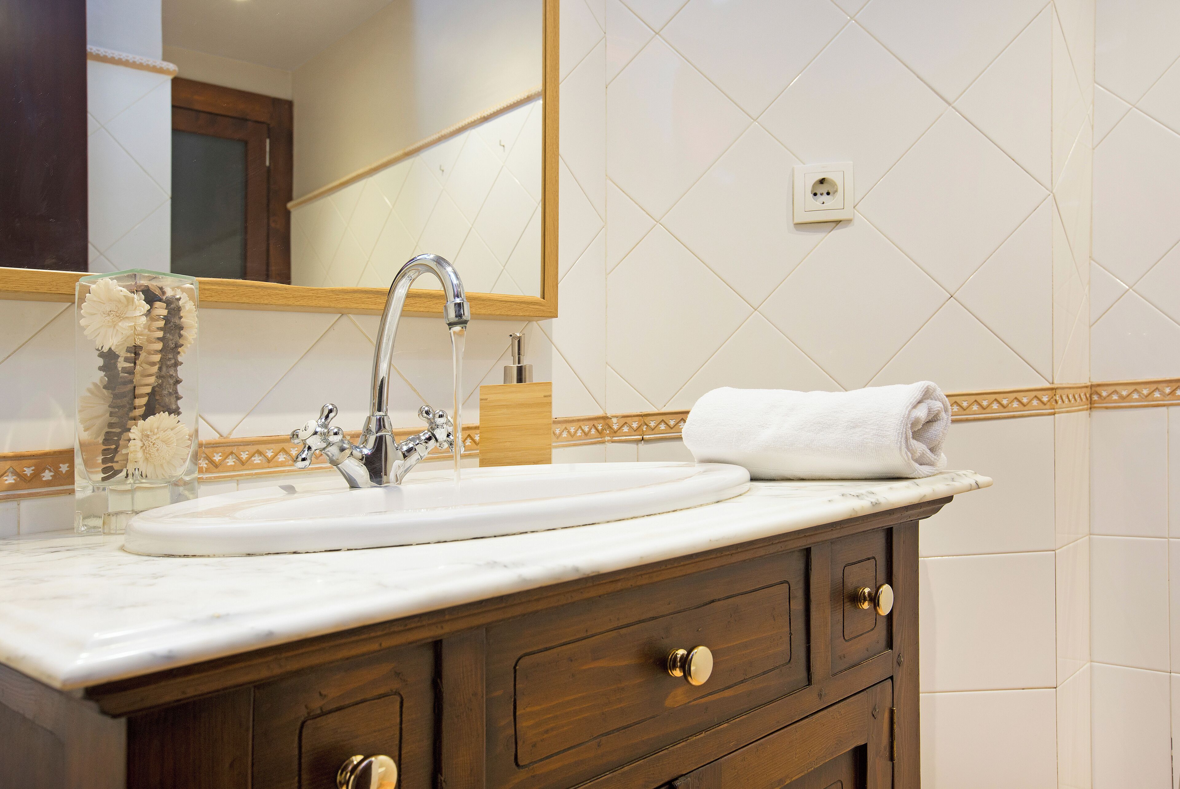 Une salle de bain avec un lavabo blanc, un miroir et un meuble-lavabo en bois doté de tiroirs.