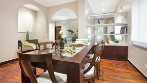 A dining area with a glass-top table, wooden chairs, and a buffet setup. - Stay U-nique Apartments Calvet (Barcelona)