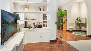 A modern living room with a white entertainment unit, a flat-screen TV, and a large plant. - Stay U-nique Apartments Calvet (Barcelona)