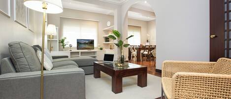 A modern living room with a grey sofa, a wicker chair, a wooden coffee table, and a floor lamp.