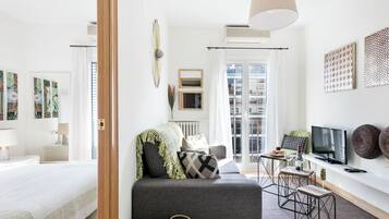 A modern living room with a sofa, a TV, and a dining area.