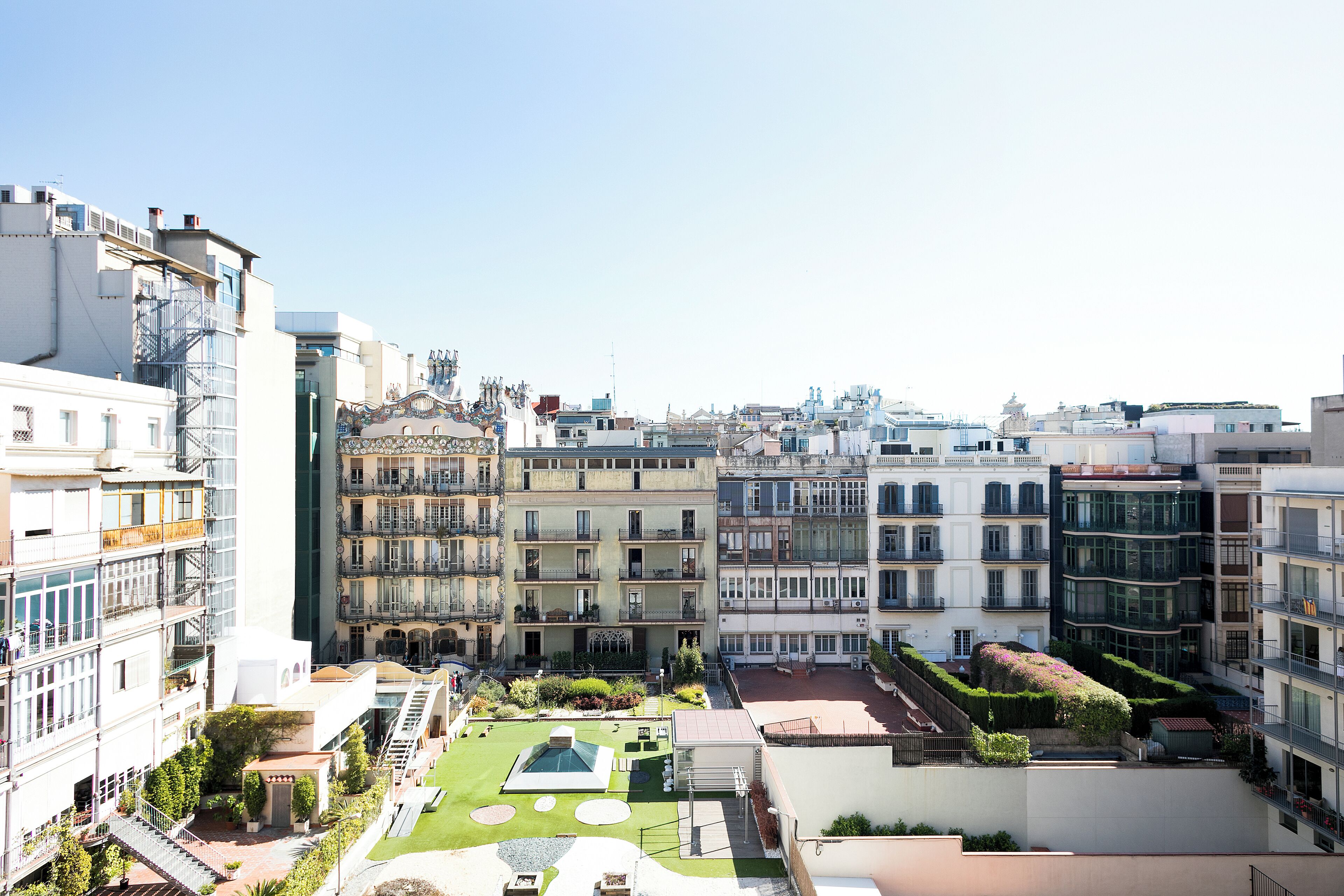 Um edifício residencial com vários andares, varandas, um pátio com piscina e vista para a paisagem urbana.