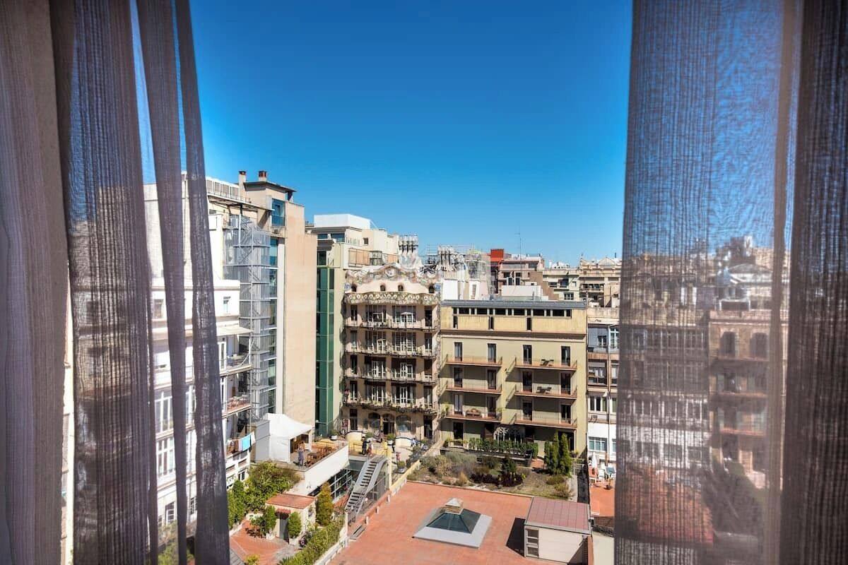Vista de un paisaje urbano a través de una ventana con cortinas.