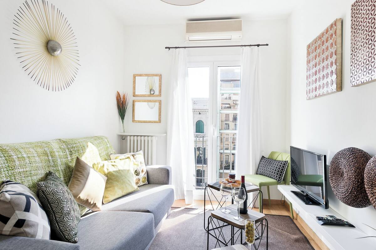 Una sala de estar moderna con sofá, televisor y comedor.