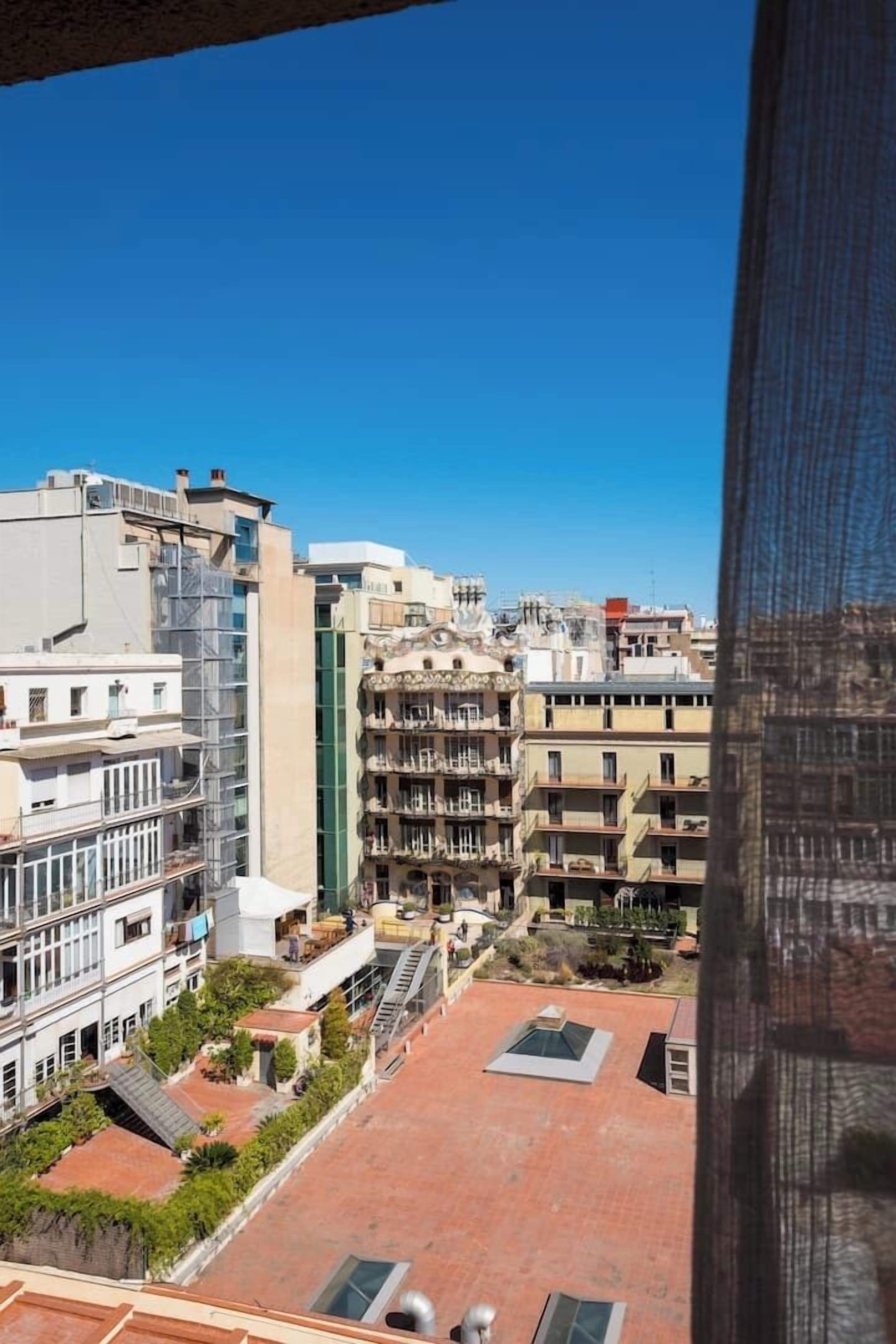 Vista de un paisaje urbano con varios edificios, incluyendo un edificio blanco destacado con fachada verde y una estructura alta con techo azul.
